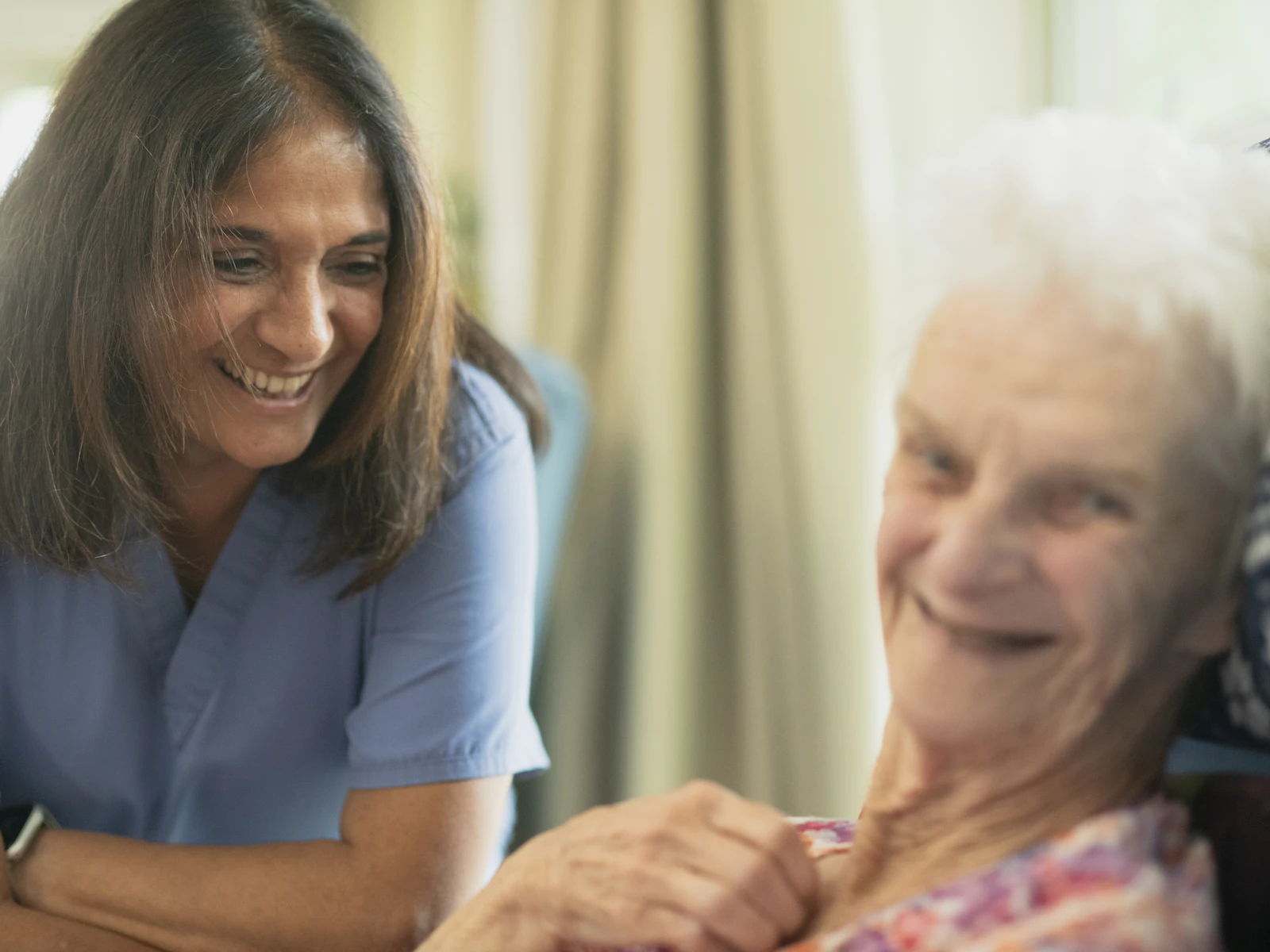 A caregiver smiling warmly with an elderly patient